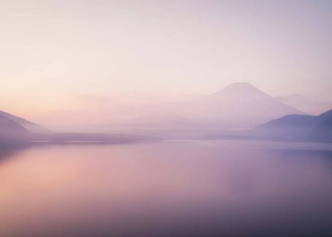 - Landscape photo of a foggy lake and the peak of Mount Fuji in the background.