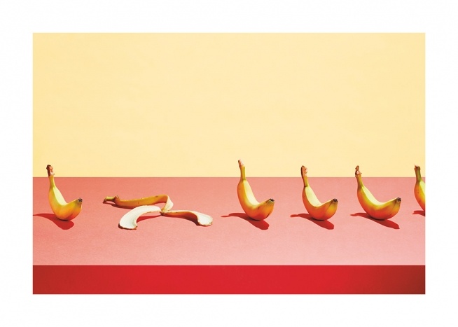  – Photograph of a row of bananas laying on a pink table against a yellow background